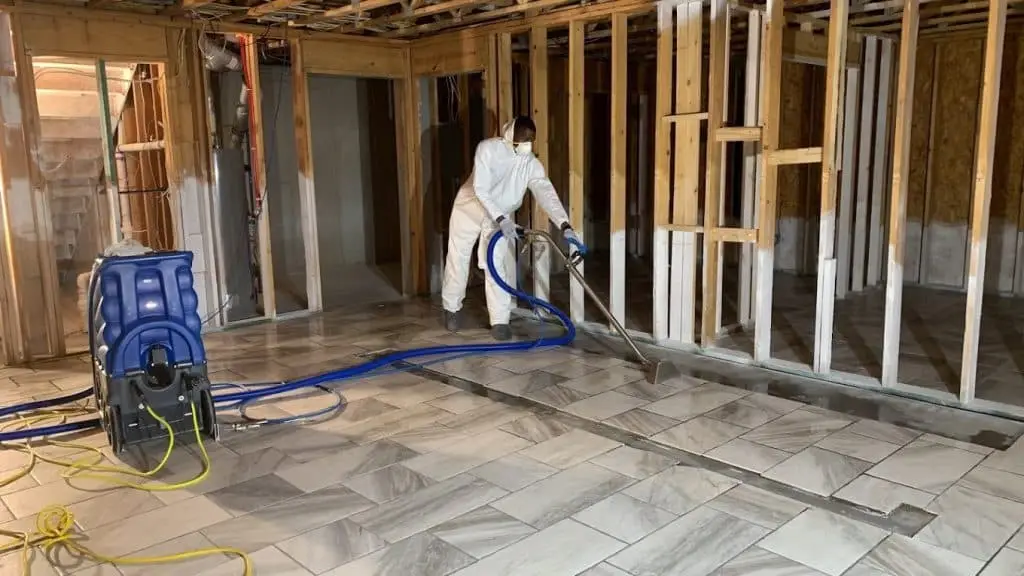 Dry Pros technician in PPE performing water extraction and structural drying after a water damage event, Austell GA